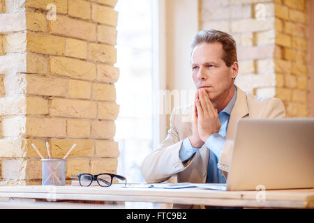 Thoughtful man sitting at the table Stock Photo