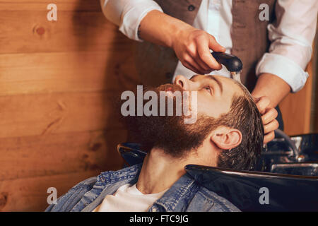 Barber washing head of bearded man Stock Photo