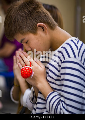 Bangkok, Bangkok, Thailand. 27th Mar, 2016. A young man prays with an Easter egg hanging off his finger during Easter services at Santa Cruz Church in Bangkok. Santa Cruz was one of the first Catholic churches established in Bangkok. It was built in the late 1700s by Portuguese soldiers allied with King Taksin the Great in his battles against the Burmese who invaded Thailand (then Siam). There are about 300,000 Catholics in Thailand, in 10 dioceses with 436 parishes. Easter marks the resurrection of Jesus after his crucifixion and is celebrated in Christian communities around the world. (Cre Stock Photo