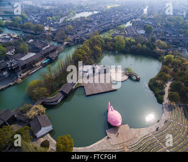 Tongxiang, China. 27th March, 2016. Photo taken on March 27, 2016 shows a giant pink 'Floating Fish' on the water theatre in Wuzhen, east China's Zhejiang Province. The pink 'Floating Fish' is a piece of works designed by Florentijn Hofman, who is also know for creating a huge 'Rubber Duck' in Hong Kong in 2013, for the Wuzhen International Contemporary Art Exhibition. The 'Floating Fish' is made of floating plates for swimming. The exhibition will be held here from March 28 to June 26. Credit:  Xinhua/Alamy Live News Stock Photo