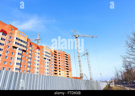 Crane and building construction site against blue sky. Stock Photo