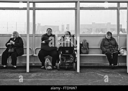 A candid image of four overweight people sitting in a beach shelter at Skegness, Lincolnshire, UK Stock Photo