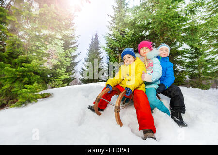 Three little children on sledge in park Stock Photo