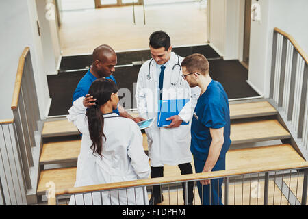 Confident team of doctors talking about a patient looking at tablet Stock Photo