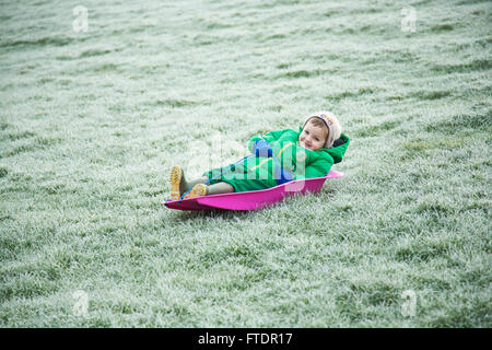 Sledging on frosty grass without proper snow Stock Photo