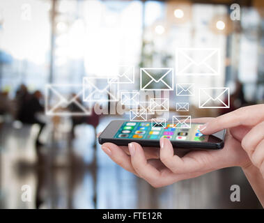 Smart phone emitting holographic image of social media related icons. Hand touching touch smart phone, social media concept. Blurred city background. Stock Photo