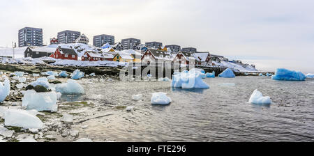 Drifting icebergs, old harbor buildings and living blocks of Nuuk city, Greenland Stock Photo