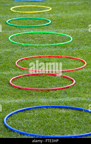 Coloured hoope lined up on a school field ready for the sports day obstacle race. Stock Photo