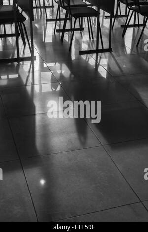 Rows and lines of empty conference chairs caught in natural sunlight in a classroom school environment. Black and white image wi Stock Photo