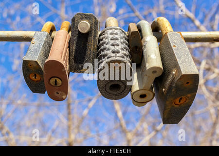 Line of old rusting metal padlocks locked and secured. Defocused tree background area with copy space for love as eternity, and Stock Photo