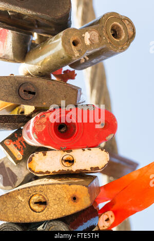 Line of various old rusting metal padlocks in different shapes locked and secured. Blue clear background sky area with copy spac Stock Photo