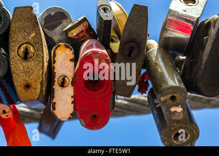 Line of various old rusting metal padlocks in different shapes locked and secured. Blue clear background sky area with copy spac Stock Photo