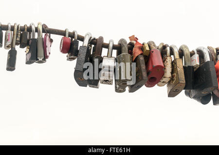 Line of various old rusting metal padlocks in different shapes locked and secured. White background sky area with copy space for Stock Photo