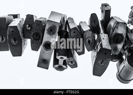 Line of old rusting metal padlocks locked and secured. White background sky area with copy space for love as eternity, and symbo Stock Photo