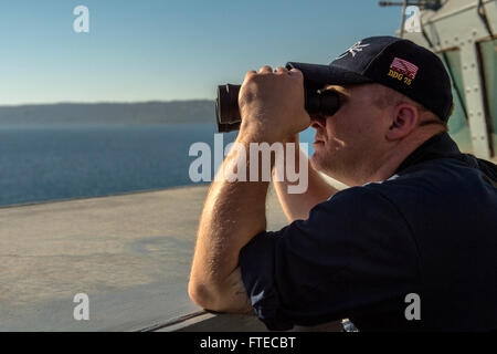 140318-N-KE519-085 SOUDA BAY, Crete (March 18, 2014) - Sonar Technician Surface 1st Class John Galliher uses binoculars to track air and surface contacts aboard the forward-deployed Arleigh Burke-class guided-missile destroyer USS Donald Cook (DDG 75) as the ship enters port in Souda Bay. Donald Cook, the first of four Arleigh Burke-class destroyers to be forward-deployed to Rota, Spain is serving on a scheduled patrol to the U.S. 6th Fleet area of operations as part of the President's Phased Adaptive Approach to European ballistic missile defense. (U.S. Navy photo by Mass Communication Specia Stock Photo