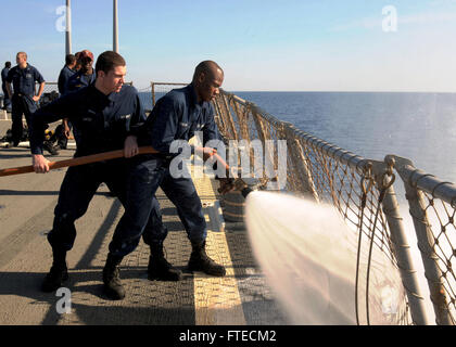 140323-N-CH661-014 MEDITERRANEAN SEA (March 22, 2014) - Hull Maintenance Technician Fireman Kwesi Jordan, right, and Damage Controlman Fireman Domenic Sacco, both assigned to the guided-missile destroyer USS Ramage (DDG 61), spray a fire hose during a timed event as a part of Damage Control Olympics. Ramage, homeported in Norfolk, Va., is on a scheduled deployment supporting maritime security operations and theater security cooperation efforts in the U.S. 6th Fleet area of operations. (U.S. Navy photo by Mass Communication Specialist 2nd Class Jared King/Released)   Join the conversation on Tw Stock Photo