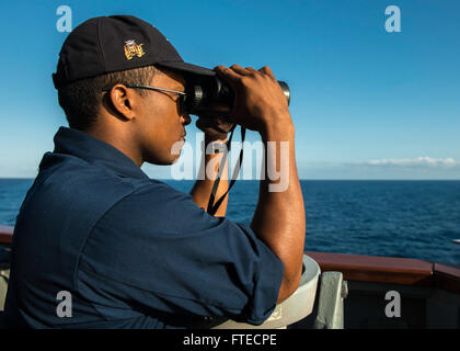 MEDITERRANEAN SEA (March 26, 2014) - Ensign Brandon Baxter uses binoculars to scan the horizon for surface contacts aboard the forward-deployed Arleigh Burke-class guided-missile destroyer USS Donald Cook (DDG 75) during a surface exercise as part of exercise Noble Dina. Donald Cook, the first of four Arleigh Burke-class destroyers to be forward-deployed to Rota, Spain, is serving on a scheduled patrol to the U.S. 6th Fleet area of operations as part of the President's Phased Adaptive Approach to European ballistic missile defense. Stock Photo