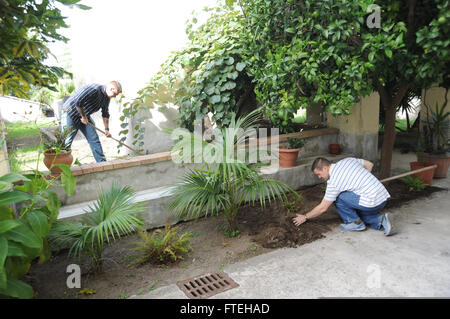 NAPLES, Italy (Oct. 13, 2014) - Staff Sgt. James Mackenzie, left, and Cmdr. Anthony Savage assist in yard work for a local church during community relations project in Naples, Italy. Bataan, homeported in Norfolk, Va., is conducting naval operations in the U.S. 6th Fleet area of operations in support of U.S. national security interests in Europe. Stock Photo