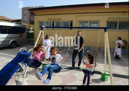 NAPLES, Italy (Oct. 13, 2014) - Sailors and Marines assigned to the amphibious assault ship USS Bataan (LHD 5) play with the children at a daycare run by the Franciscan Sisters of the Sacred Heart during a community relations event in Naples, Italy. Bataan, homeported in Norfolk, Va., is conducting naval operations in the U.S. 6th Fleet area of operations in support of U.S. national security interests in Europe. Stock Photo