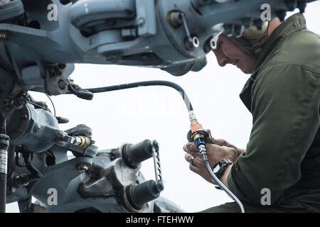 MEDITERRANEAN SEA (Oct. 29, 2014) – Aviation Electrician’s Mate 2nd Class Benjamin Romero, assigned to the Ghostriders of Helicopter Sea Combat Squadron (HSC 28), Detachment 1, performs maintenance on an MH-60S Sea Hawk helicopter aboard the 6th fleet command and control ship USS Whitney (LCC 20). Mount Whitney is conducting naval operations with allies and partners in the U.S. 6th Fleet area of operations in order to advance security and stability in Europe. Stock Photo