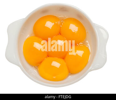 Six raw egg yolks in a white bowl Stock Photo