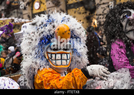 A waggis (a typical character of the Basel carnival) in yellow-white costume throwing confetti into the crowd (carnival 2016) Stock Photo