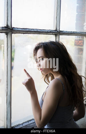 Young woman drawing with finger on a fogged window Stock Photo