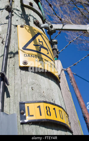 Wooden telegraph pole uk,with warning signs danger of death high voltage Stock Photo