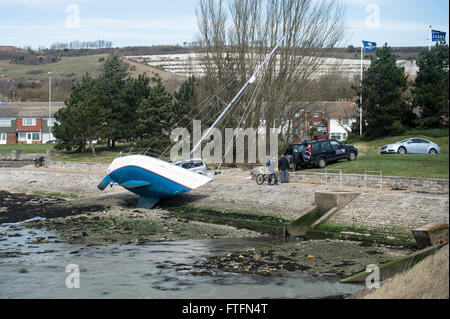 Portsmouth Harbour, Hampshire, UK. 28th March, 2016. The yacht, 'Faolan' lies almost on her side on the shore after being swept from her anchorgae during Storm Katie on Easter Monday. Credit:  Rob Wilkinson/Alamy Live News Stock Photo
