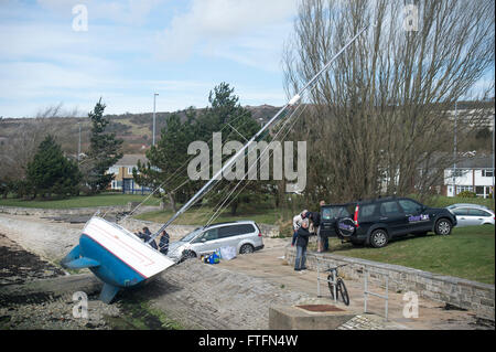 Portsmouth Harbour, Hampshire, UK. 28th March, 2016. The yacht, 'Faolan' lies almost on her side on the shore after being swept from her anchorgae during Storm Katie on Easter Monday. Credit:  Rob Wilkinson/Alamy Live News Stock Photo