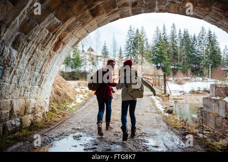 Happy young couple holding hands and running together under the bridge Stock Photo