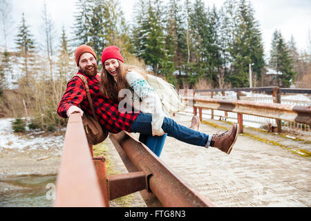 Happy young couple sitting on old bridge and having fun Stock Photo