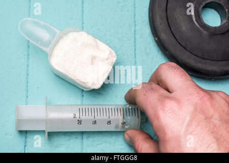 Container of milk whey protein, injection and disc from dumbbell. Close-up. Blue background Stock Photo