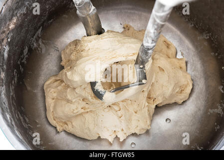 High Angle Close Up View of Dough Mixing in Industrial Mixer with Dough Hooks in Bakery Stock Photo