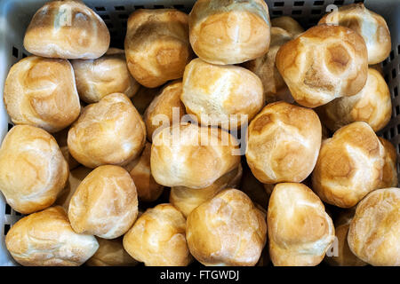Background texture of delicious crusty freshly baked white bread rolls on display for sale in a bakery, close up from above Stock Photo