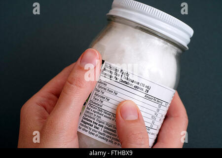 Reading a nutrition facts on organic coconut oil jar. Stock Photo