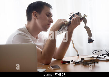 Portrait of computer young engineer working with broken pc parts sitting in the small home office Stock Photo