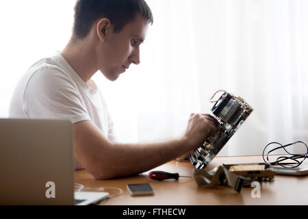Portrait of handsome young computer repairman working with broken pc parts indoors in the home office Stock Photo