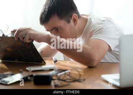 Portrait of technician repairing broken computer parts indoors at the desk in small office Stock Photo