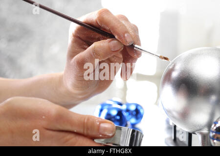 Painting Christmas balls. Manufacturing and crafts. Woman decorate baubles. Christmas tree decorations Stock Photo