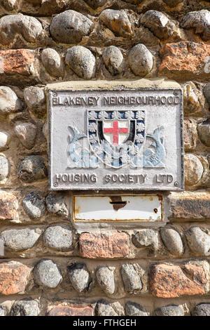 Sign and donation box for the Blakeney Neighbourhood Housing Society Ltd on the flint stone wall of a house Stock Photo