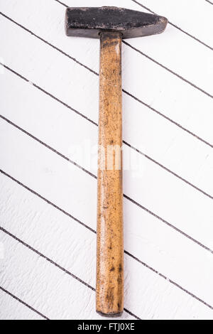 Old hammer on a white wooden background Stock Photo