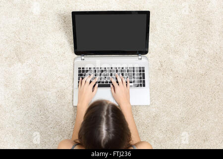 Top view of a woman working with laptop and showing blank screen lying on the floor at home Stock Photo
