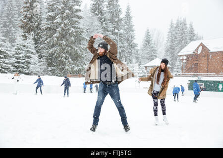 Funny young couple ice skating outdoors Stock Photo