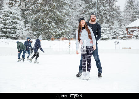 Smiling couple in ice skates standing outdoors
