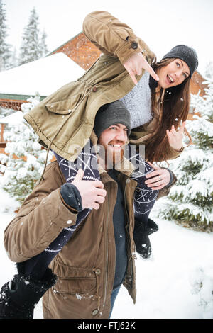 Beautiful young couple having fun and showing rock gesture in winter Stock Photo