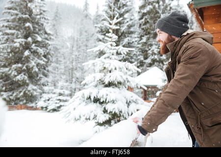 Profile of attractive happy young man with beard standing in  mountain winter forest Stock Photo