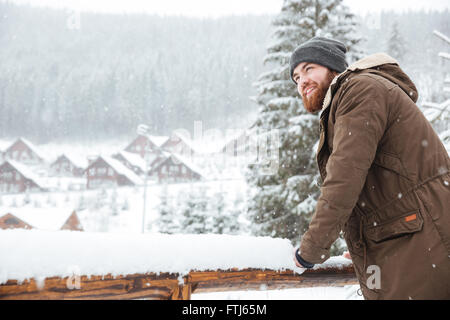 Smiling handsome bearded man standing and enjoying  snowy weather on winter resort Stock Photo
