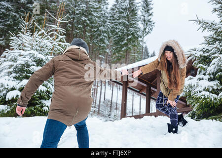 Beautiful couple reaching hands and helping each other while walking in mountains in winter Stock Photo