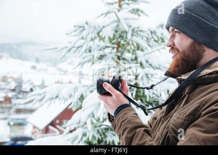 Profile of focused young man using camera and taking photos in winter Stock Photo